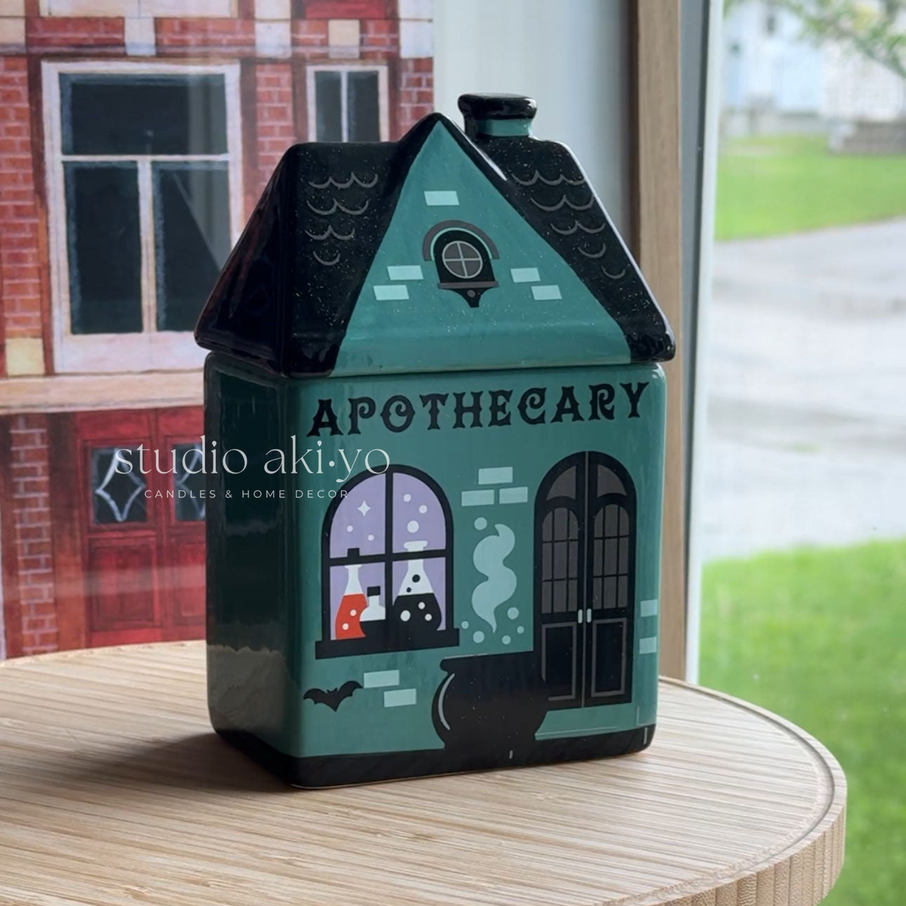 Decorative apothecary-themed house-shaped container on a wooden surface with a blurred background.
