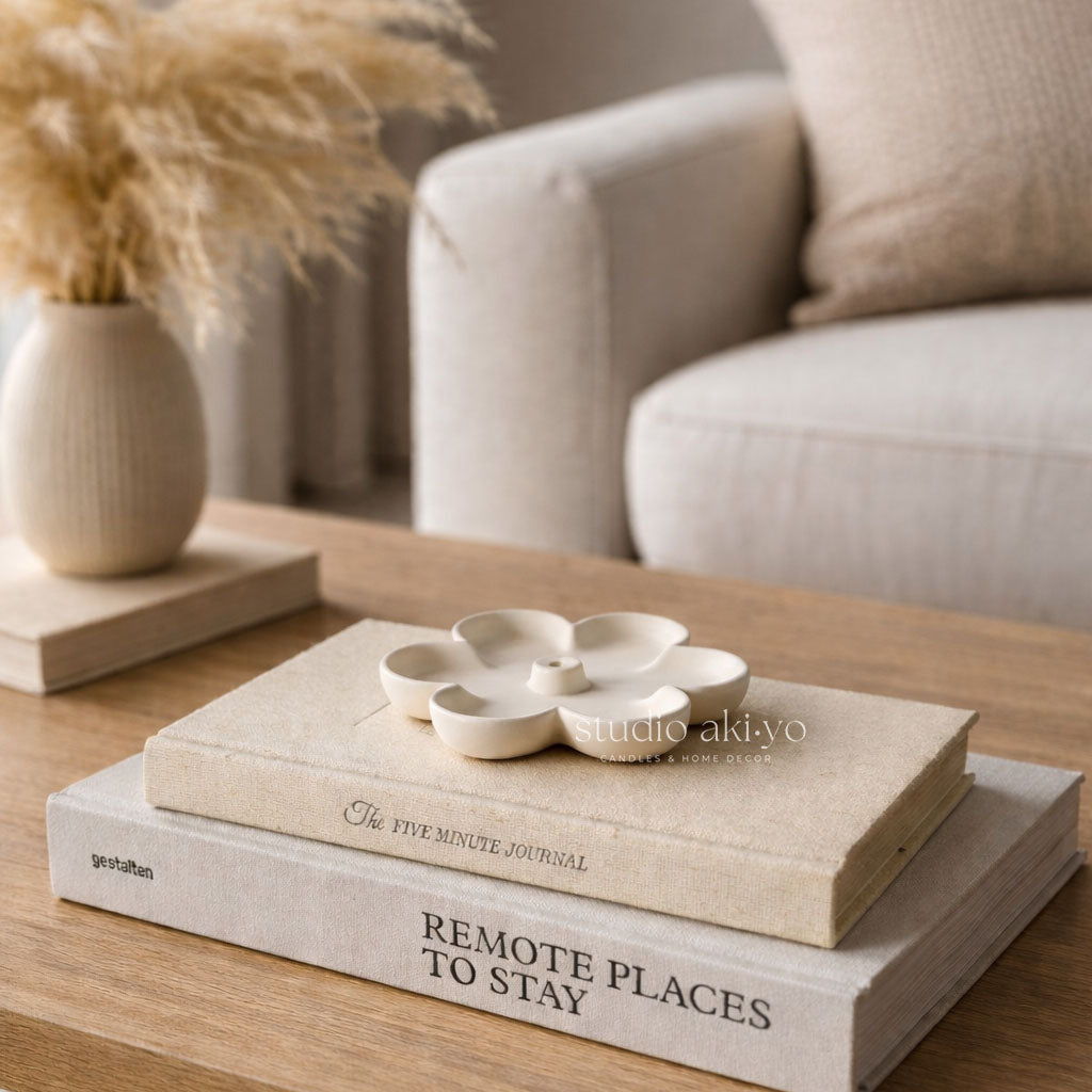 Stack of books on a wooden table with decorative items and a blurred background