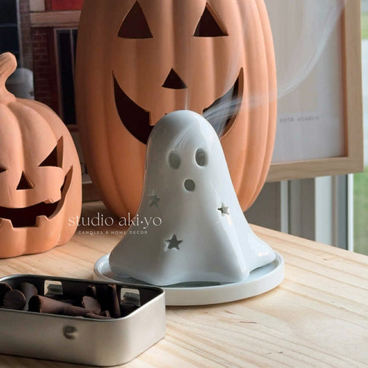 Ghost-shaped diffuser with pumpkins in the background on a wooden surface