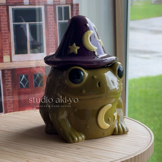 Ceramic owl with a witch hat on a wooden surface, with 'studio akiyo' branding.