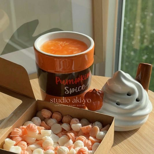 Pumpkin spice wax oil burner with decorative items on a wooden surface