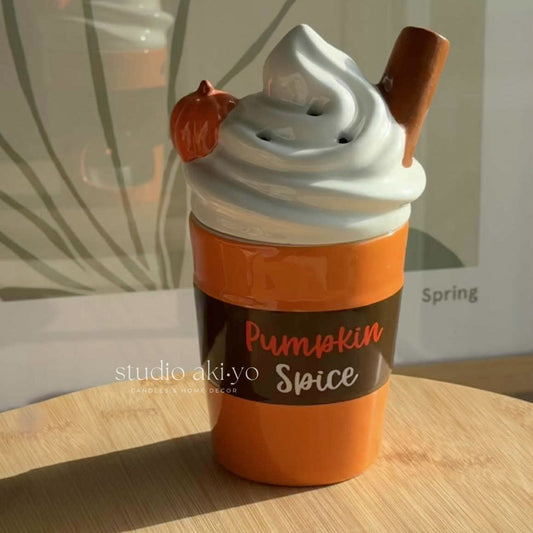 Pumpkin spice-themed ceramic wax oil burner with a lid on a wooden surface.