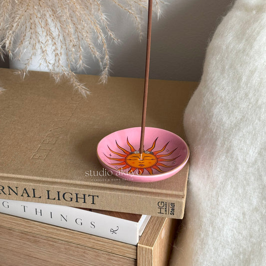 Sun incense stick holder catching ash from lit incense stick