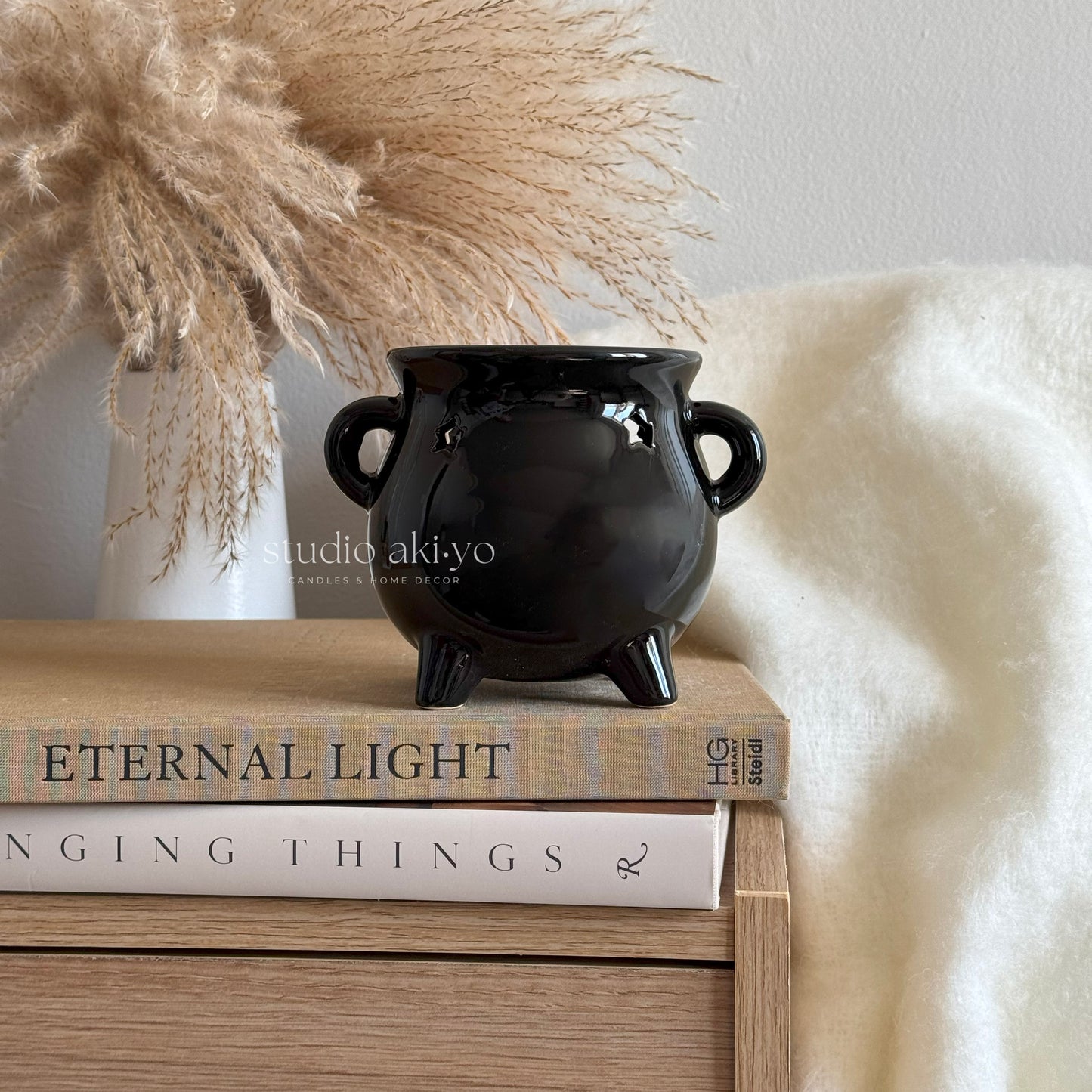 Black ceramic pot on books with decorative elements in the background