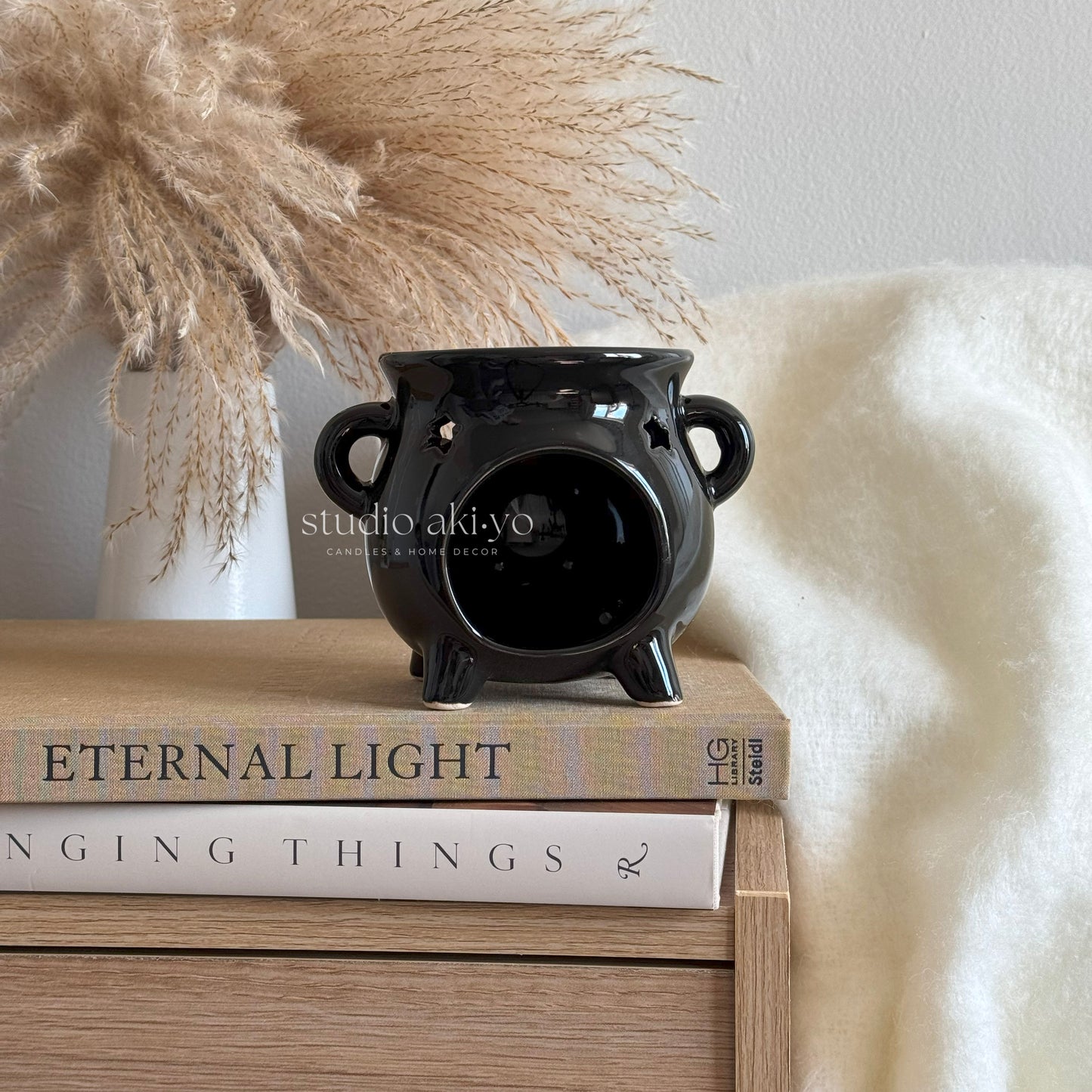 Black ceramic vase on a stack of books with decorative elements in the background