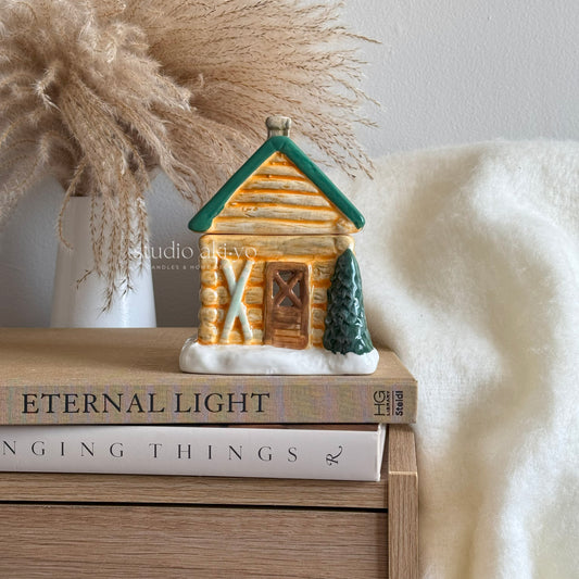 Small log cabin figurine on a stack of books with a soft white background