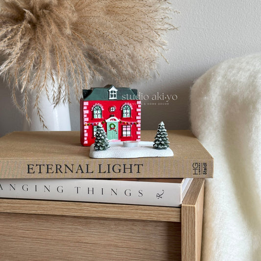 Small decorative house on top of books with 'studio aki-yo' branding