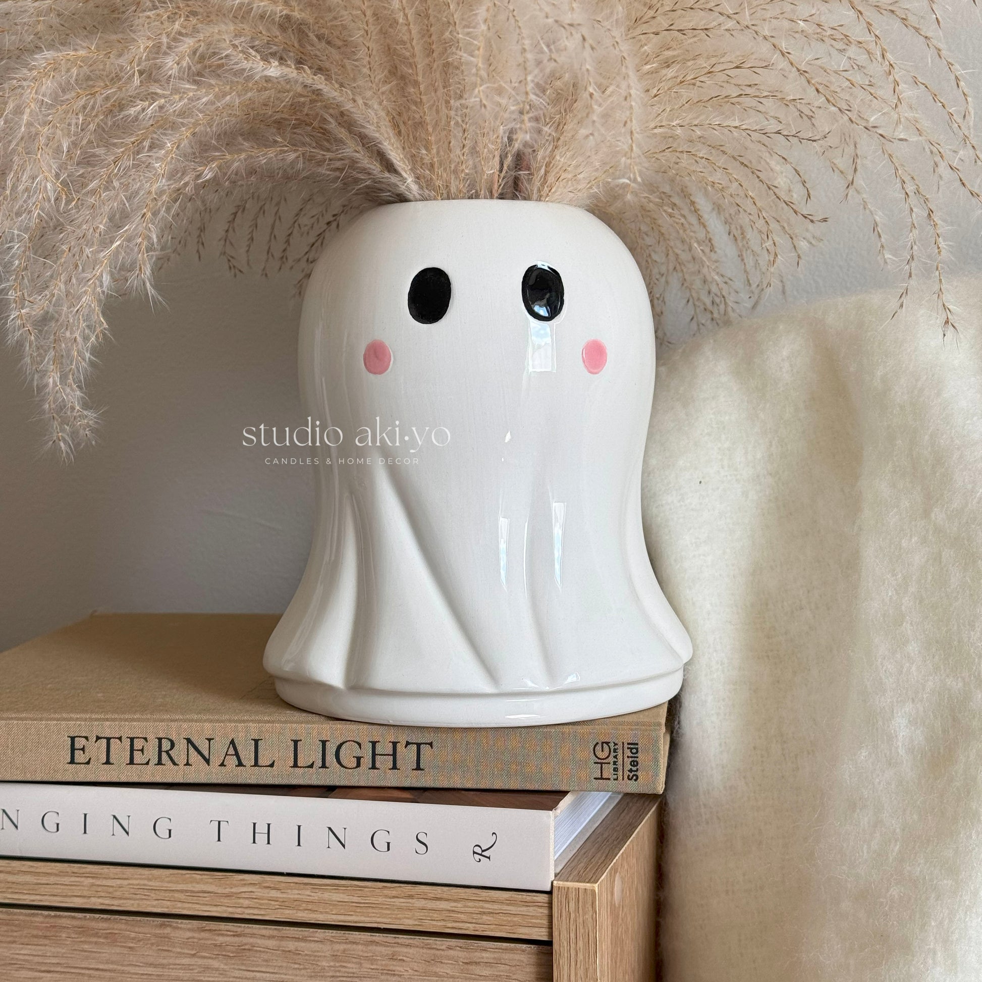 Ghost vase holding dried flowers styled in spooky Halloween décor