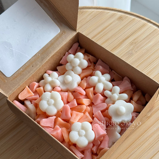 Box of pink and white floral-shaped candies on a wooden surface