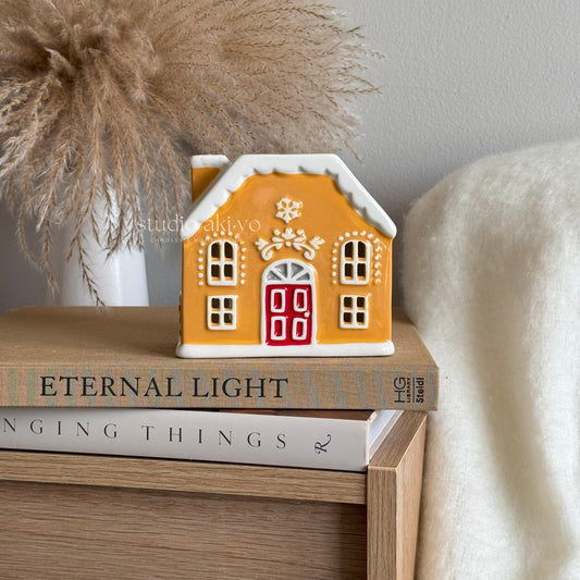 Festive gignerbread house wax melt burner on books with a neutral background