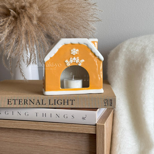 Decorative house-shaped candle holder on a stack of books with a soft background