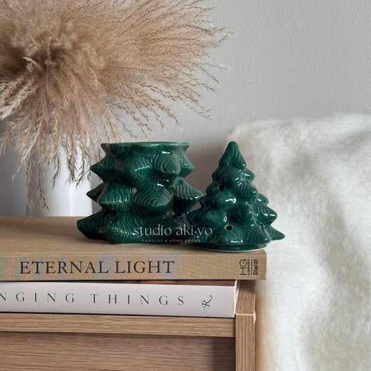 Green ceramic tree-shaped candle holders on books with decorative background