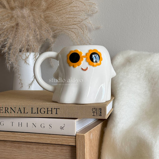 White ceramic hippie ghost mug with 60s-style sunglasses holding a brew
