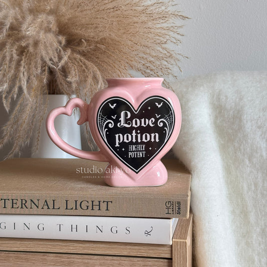 Pink heart-shaped container with 'Love potion' text on a stack of books