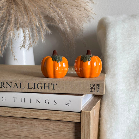 Two pumpkin-shaped ceramic spice shakers—salt and pepper set