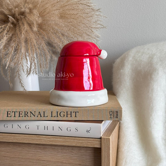 Red and white ceramic wax melt burner on a stack of books with 'studio akiyo' branding.