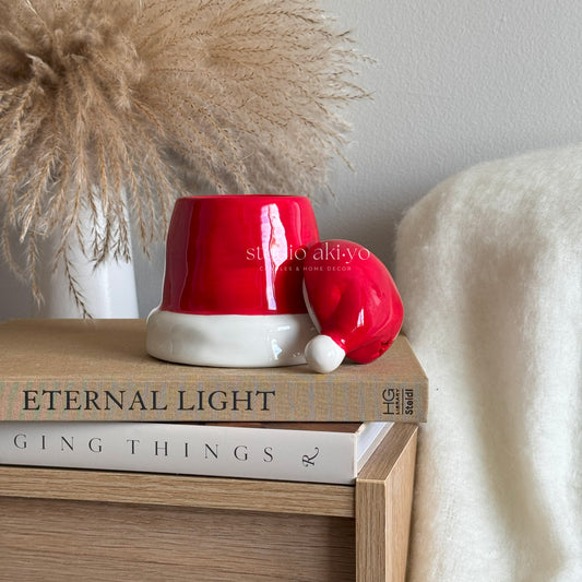 Red ceramic lamp with white base on top of books on a wooden surface.