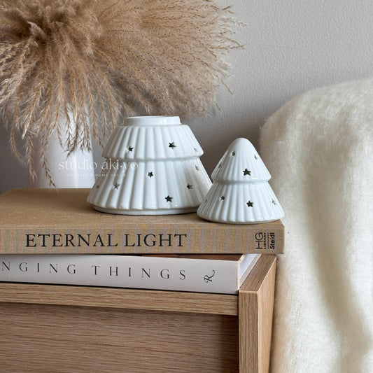 White ceramic tree-shaped wax burner on a stack of books with decorative elements.