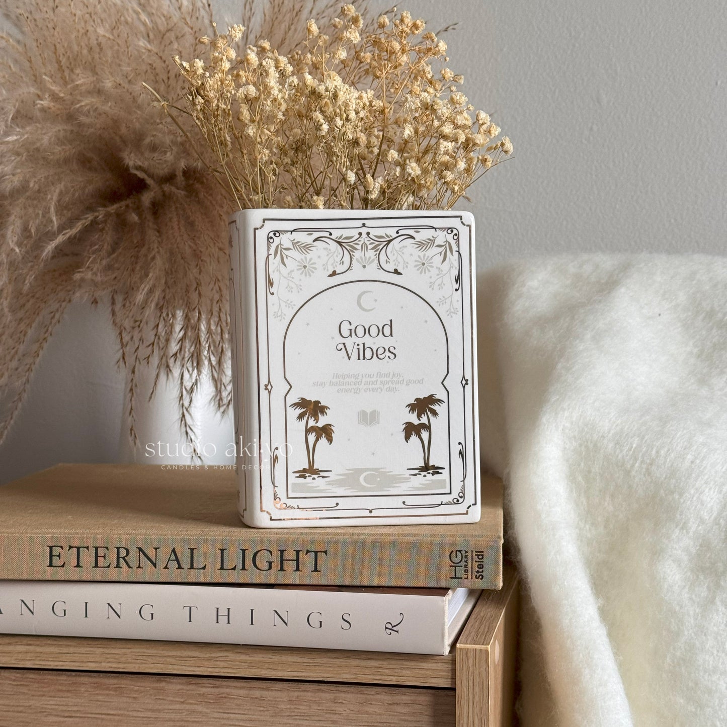Decorative container with 'Good Vibes' text on a stack of books with a soft background