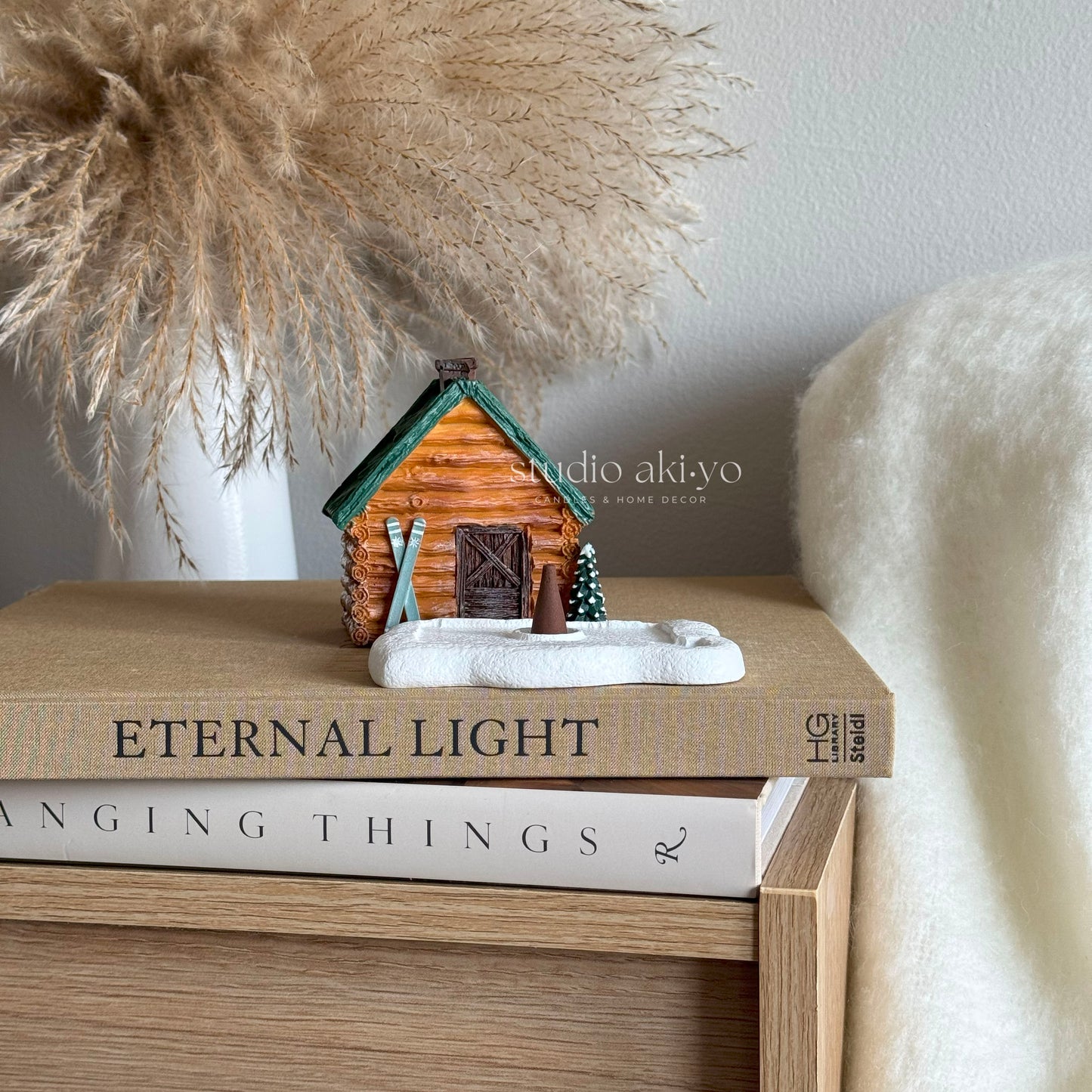 Small log cabin figurine on books with decorative elements in the background