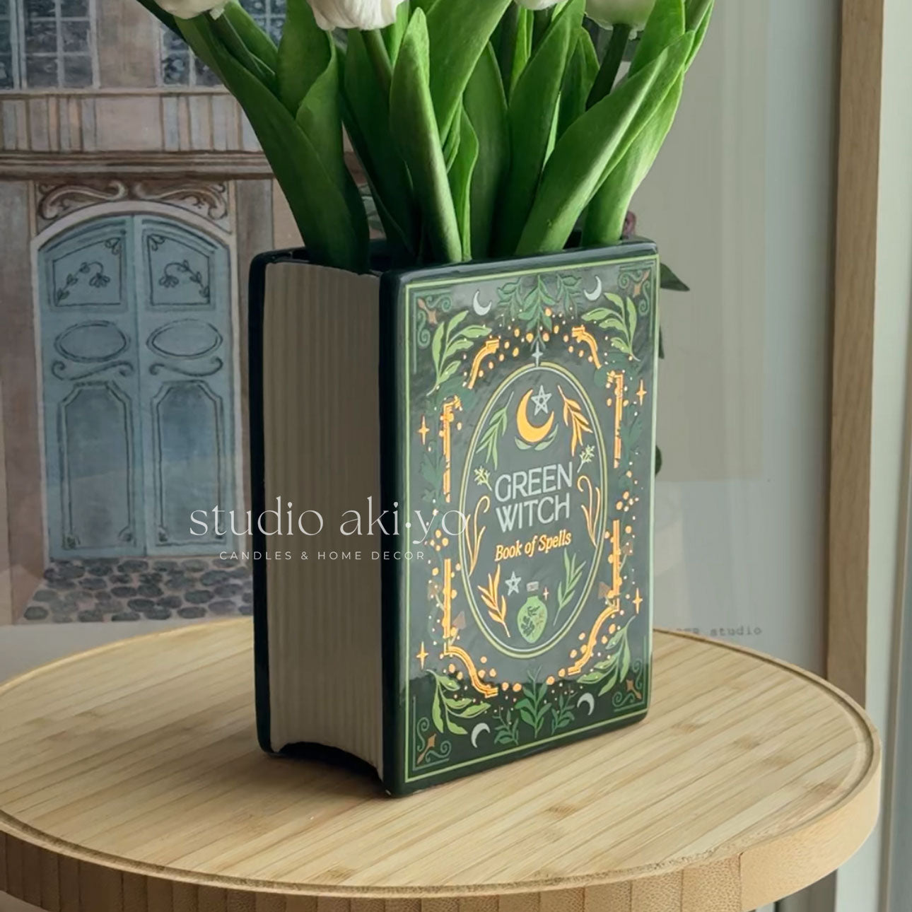 Book-shaped vase with 'Green Witch Book of Spells' design on a wooden surface.