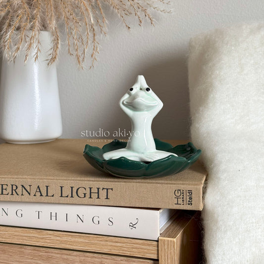 Ceramic yoga frog incense holder seated in lotus pose on lotus leaf base
