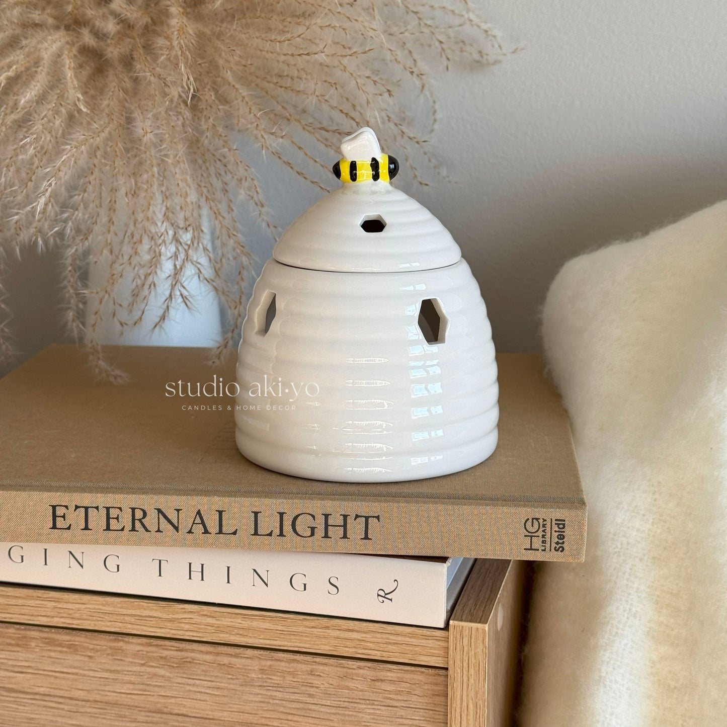 White ceramic beehive wax melt burner with honeycomb cutouts and bee on lid