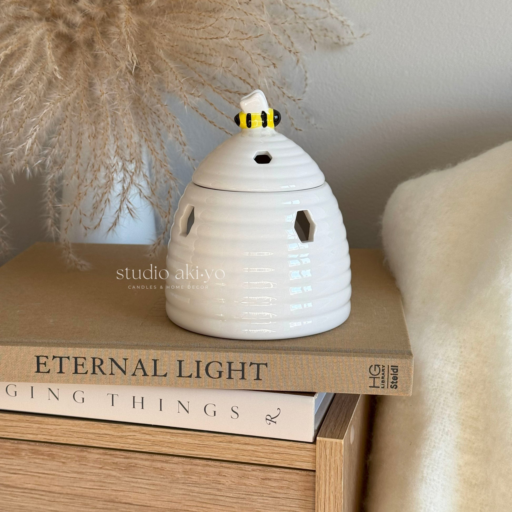 White ceramic beehive wax melt burner with honeycomb cutouts and bee on lid