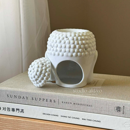 White ceramic Buddha head wax melt burner with removable top and tealight opening