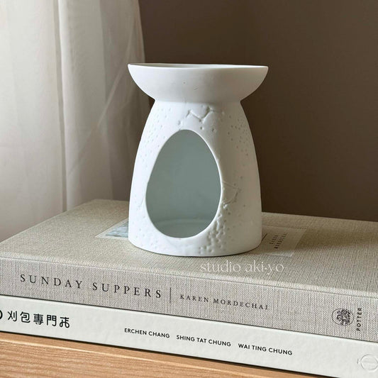 White ceramic constellation wax melt burner with star and moon cutouts and tealight opening