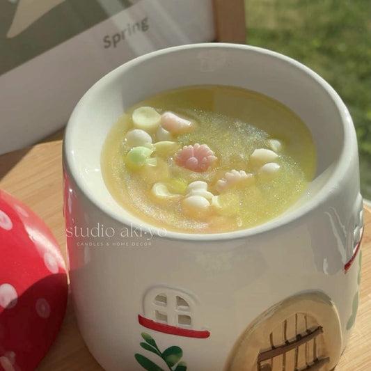 Candle with a house design emitting a warm glow, surrounded by a red polka dot object.