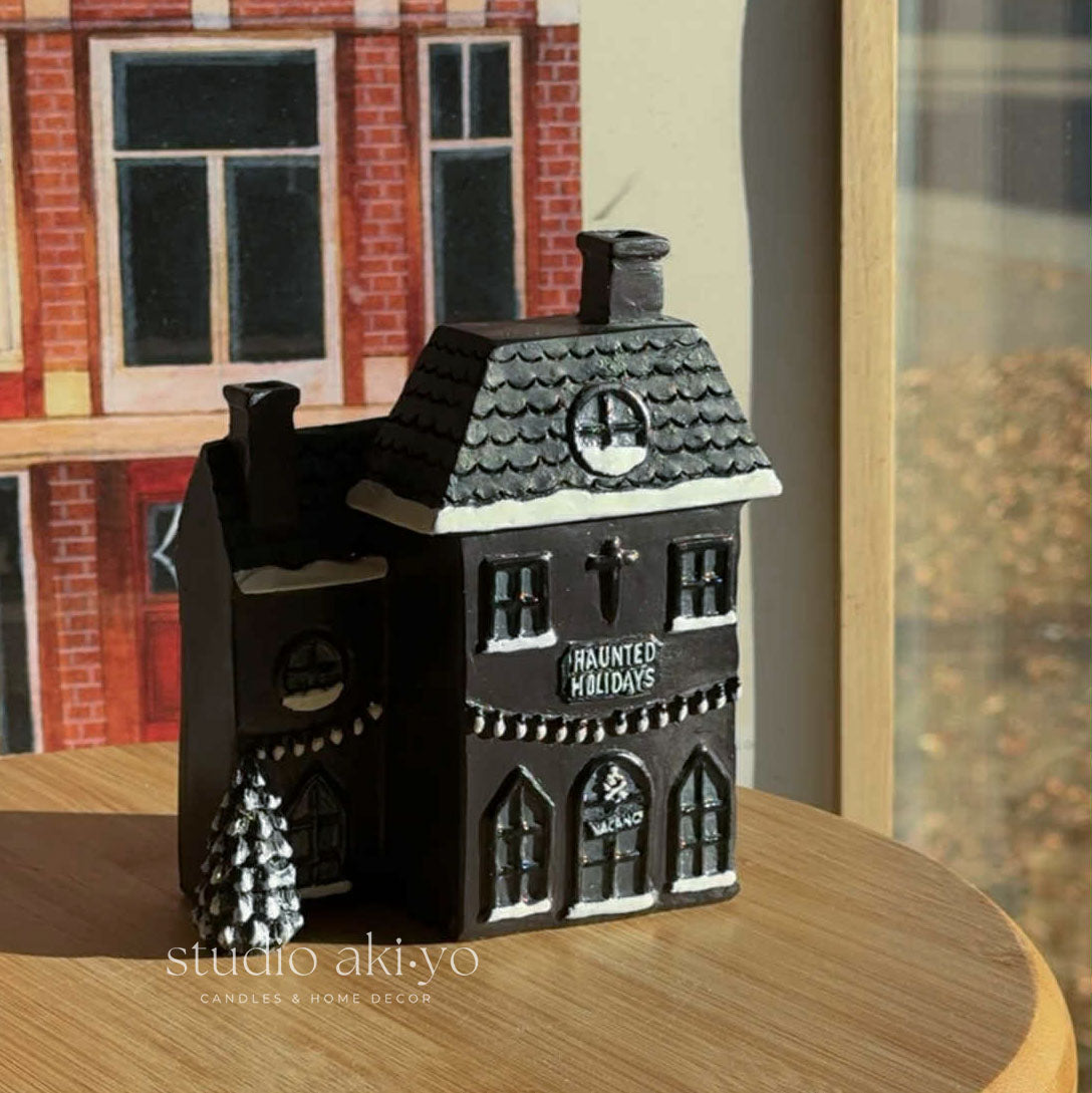 Decorative haunted house candle on a wooden surface with a blurred background