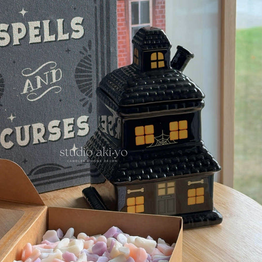 Halloween-themed black house-shaped candy container with 'Spells and Curses' text in the background.