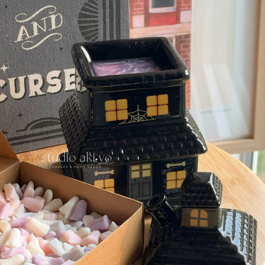 Halloween-themed black house-shaped candle with candy on a table