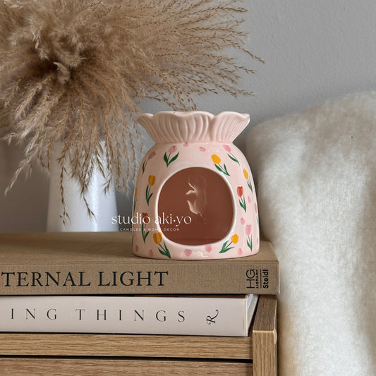 Decorative wax warmer on a stack of books with a neutral background