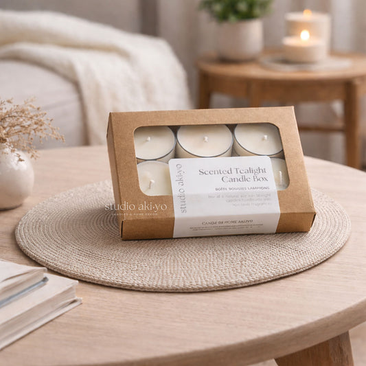 Box of scented tealight candles on a wooden table with a cozy indoor setting.