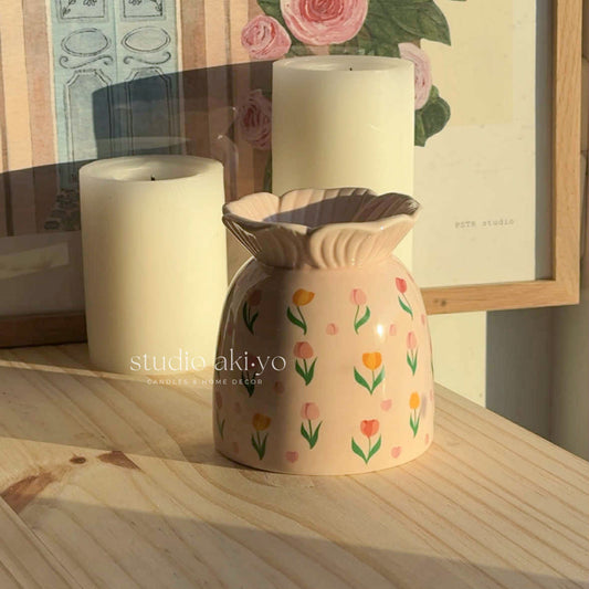 Floral-patterned wax warmer on a stack of books with decorative plants in the background