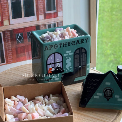 Apothecary-themed candle set with packaging on a wooden surface.