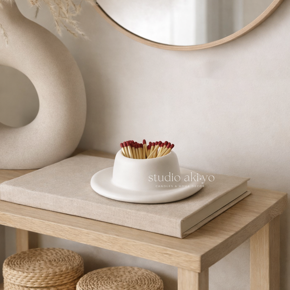 White ceramic bowl with matches on a wooden surface, featuring 'studio akiko' branding.