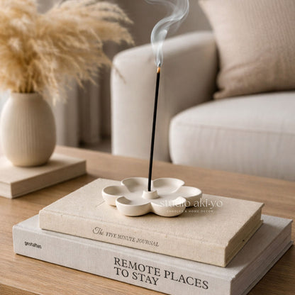 Incense stick burning in a decorative holder on top of books with a blurred background