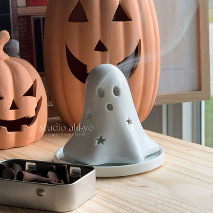 Ghost-shaped diffuser with pumpkins in the background on a wooden surface