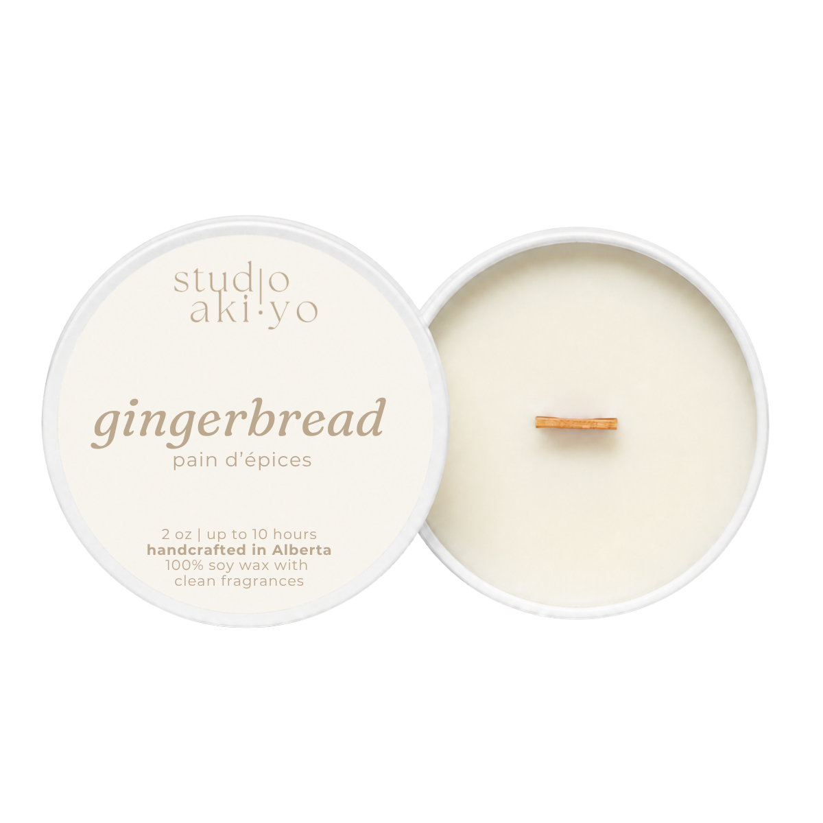 A round soy wax candle shown open with the cream-colored lid beside it on a white background. The lid reads 'studio aki·yo gingerbread pain d’epices' and the wax inside has a small wooden wick.