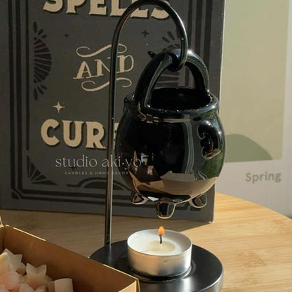 Black ceramic incense burner with a lit candle on a wooden surface, with 'studio akiko' branding in the background.