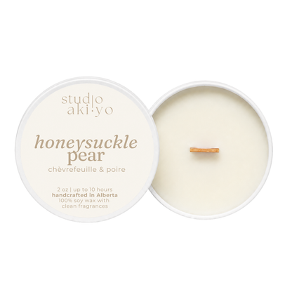 A round soy wax candle shown open with the cream-colored lid beside it on a white background. The lid reads 'studio aki yo' and 'honeysuckle pear' with smaller text 'châfrefeuille & poire.