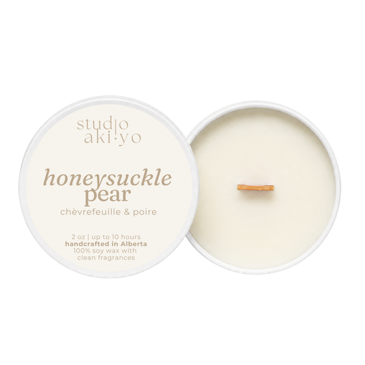 A round soy wax candle shown open with the cream-colored lid beside it on a white background. The lid reads 'studio aki yo' and 'honeysuckle pear' with smaller text 'châfrefeuille & poire.