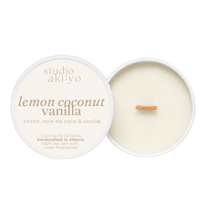 A round soy wax candle shown open on a white background, with the lid beside it. The lid is cream-colored with brown text reading 'studio aki yo lemon coconut vanilla' and additional scent text below.