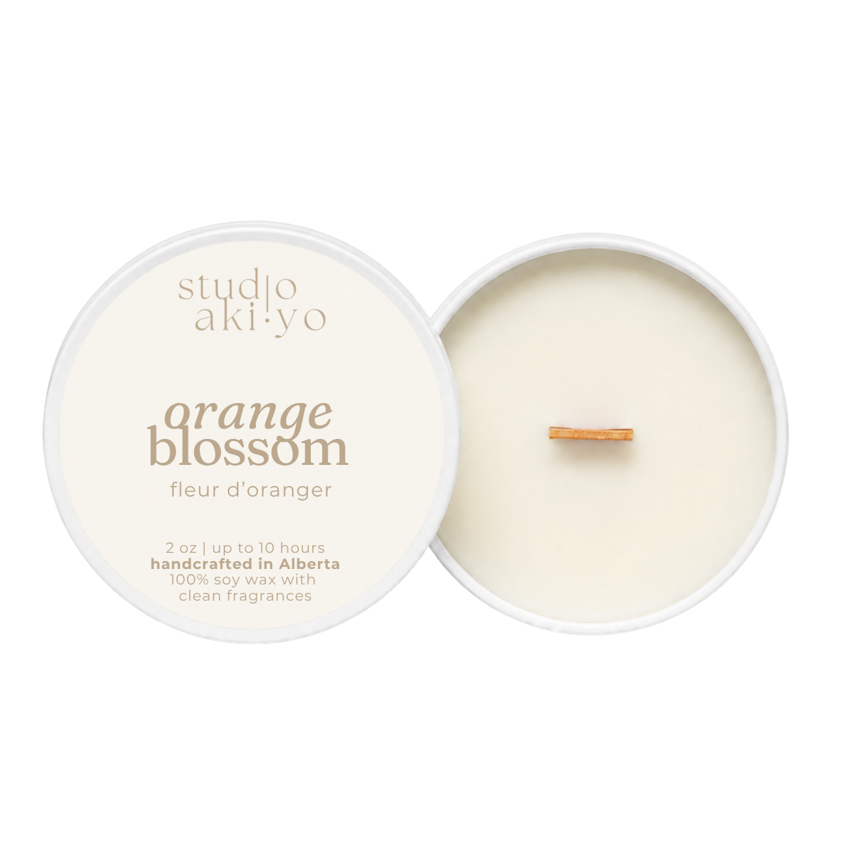A soy wax candle by studio aki yo named 'orange blossom', shown with its cream-colored lid featuring gold text next to the open candle container displaying the creamy wax and a small wooden wick.