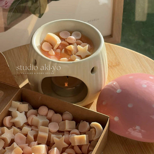 Candle warmer with decorative wax pieces on a wooden table, featuring 'studio akiyo' branding.