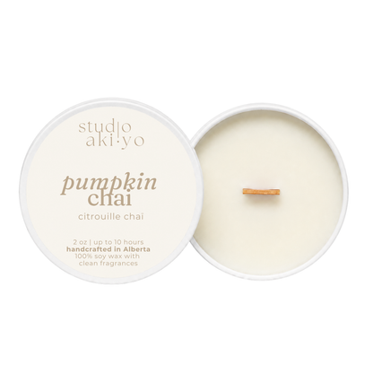 A round soy wax candle shown open with the cream-colored lid beside it on a white background. The lid reads 'studio aki yo' and 'pumpkin chai' with smaller text 'citrouille chai.