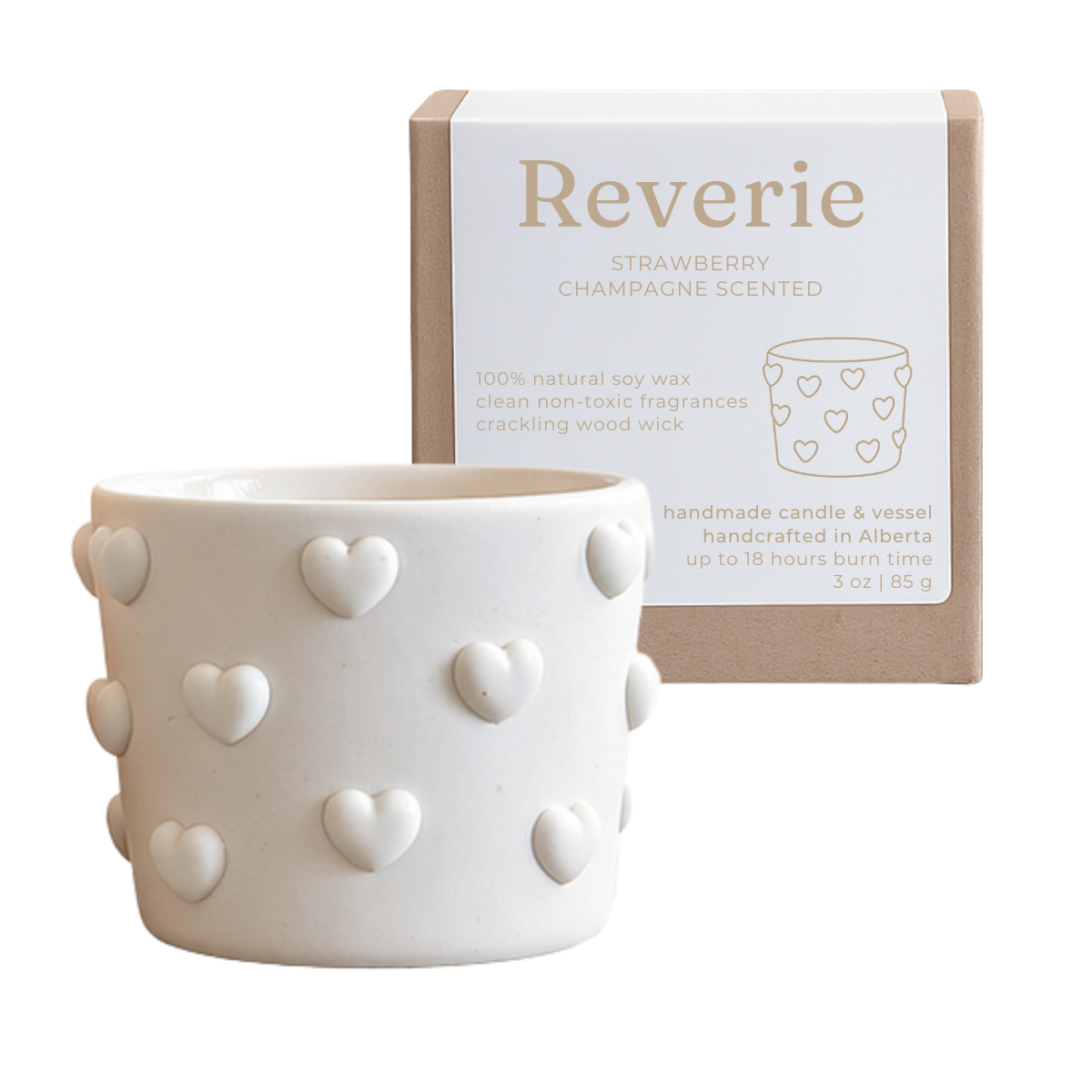 White candle with heart patterns and packaging labeled 'Reverie' on a white background